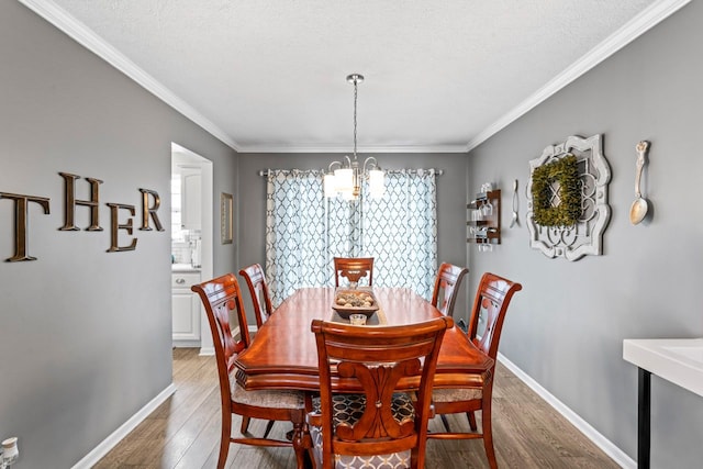 dining space featuring light wood-style flooring, crown molding, baseboards, and a notable chandelier