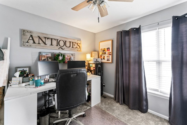 carpeted office space featuring ceiling fan and baseboards