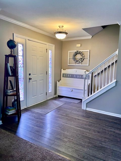 entryway featuring stairs, ornamental molding, wood-type flooring, and baseboards