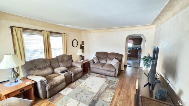 living room with arched walkways and wood finished floors