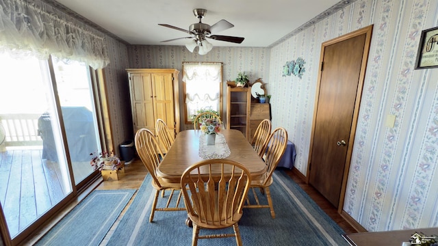 dining space with baseboards, ceiling fan, wood finished floors, and wallpapered walls