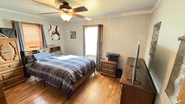 bedroom with ceiling fan, ornamental molding, and wood finished floors