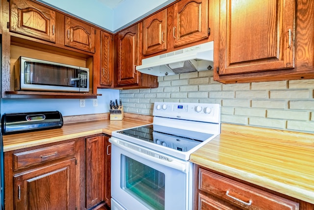 kitchen featuring white electric range oven, wood counters, stainless steel microwave, under cabinet range hood, and backsplash