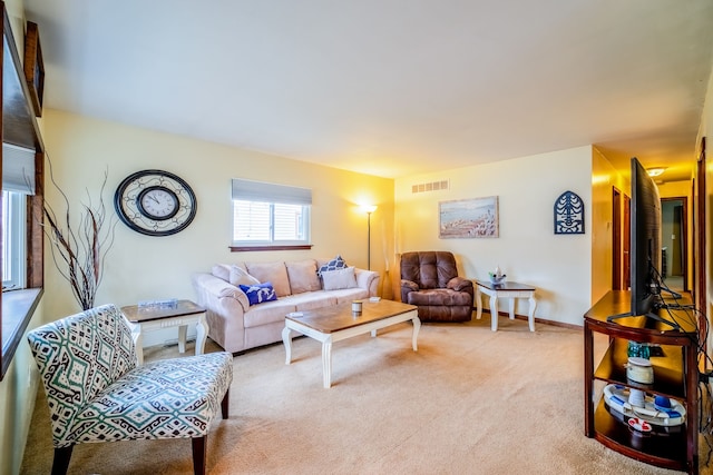 living room with baseboards, visible vents, and light colored carpet