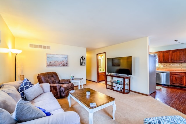 living area featuring visible vents, baseboards, and wood finished floors