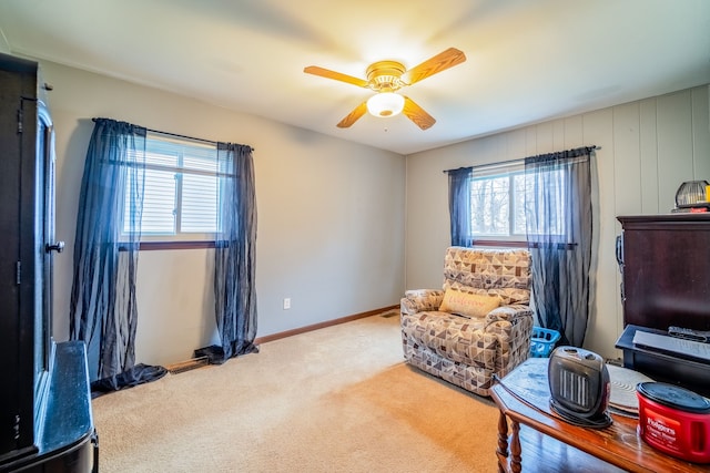 living area featuring carpet floors, baseboards, and a ceiling fan