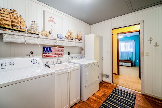 laundry room with a sink, washing machine and dryer, visible vents, and wood finished floors