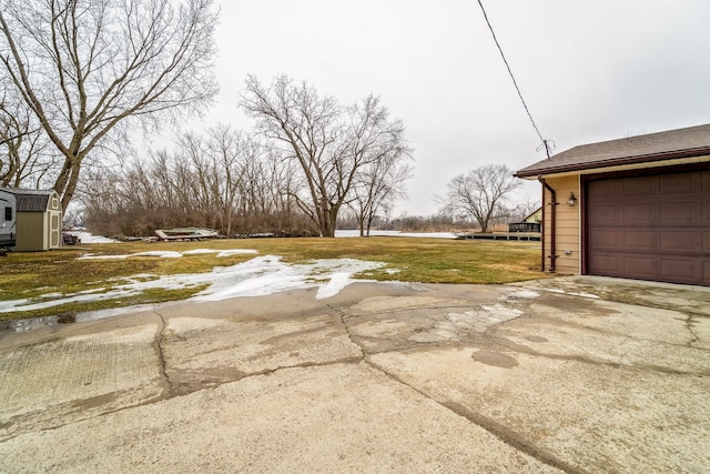 view of yard with a garage, concrete driveway, and an outbuilding