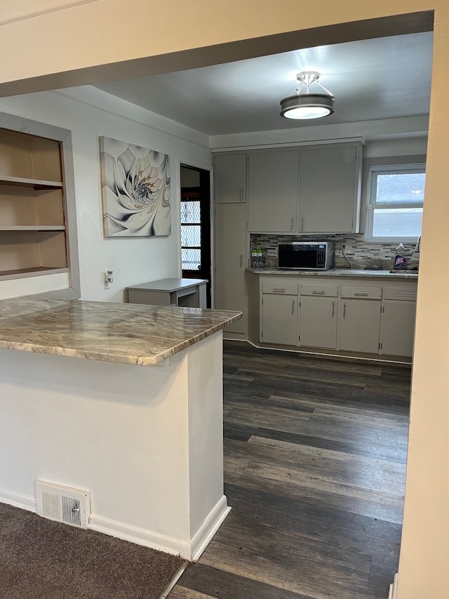 kitchen with gray cabinets, backsplash, dark wood finished floors, and visible vents