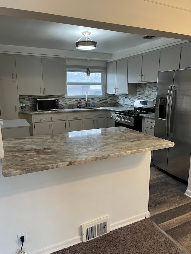 kitchen featuring visible vents, a sink, gray cabinets, stainless steel appliances, and backsplash