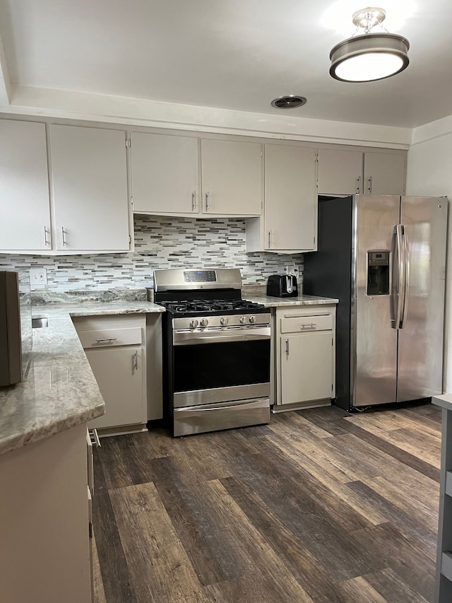 kitchen with light stone countertops, tasteful backsplash, appliances with stainless steel finishes, and dark wood finished floors