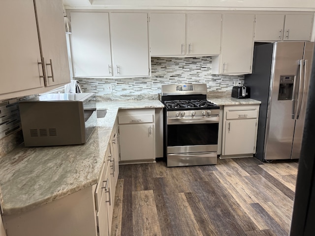 kitchen featuring stainless steel appliances, light stone counters, dark wood-style flooring, and backsplash