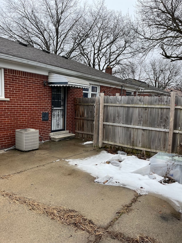 exterior space featuring cooling unit, brick siding, fence, and a chimney