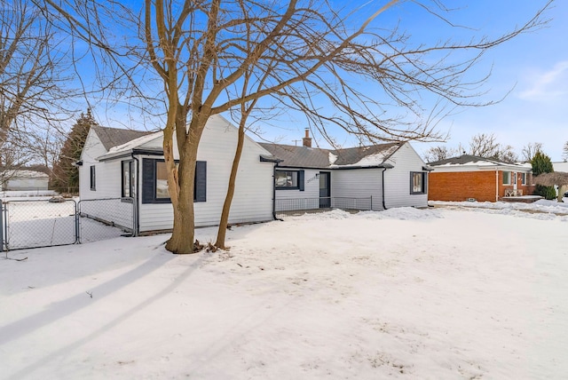 snow covered property featuring a chimney, fence, and a gate