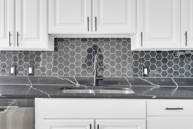 kitchen featuring decorative backsplash, white cabinets, dark stone counters, stainless steel dishwasher, and a sink