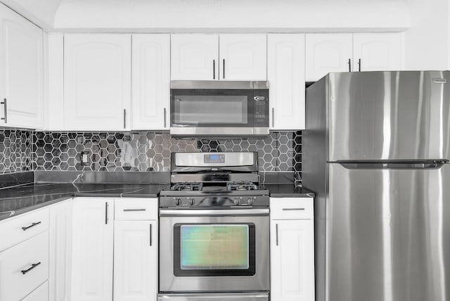 kitchen with stainless steel appliances, tasteful backsplash, dark countertops, and white cabinetry