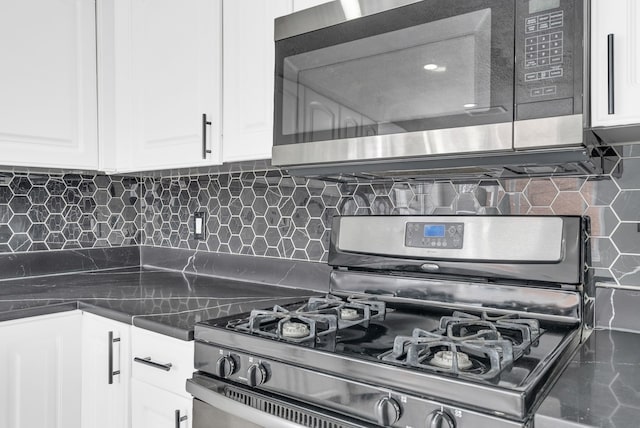 kitchen with stainless steel appliances, dark countertops, white cabinetry, and decorative backsplash