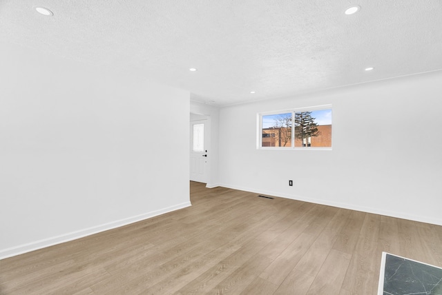 spare room with recessed lighting, baseboards, light wood-style flooring, and a textured ceiling