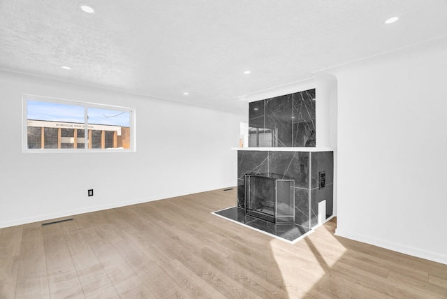 unfurnished living room with baseboards, visible vents, wood finished floors, a fireplace, and recessed lighting