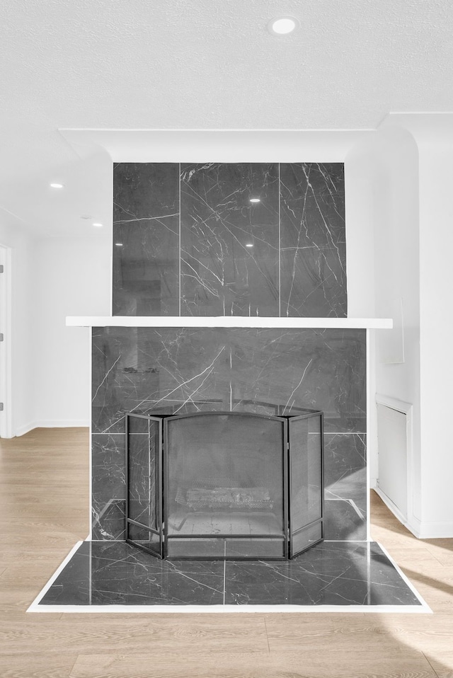 interior details featuring recessed lighting, wood finished floors, a textured ceiling, and a premium fireplace