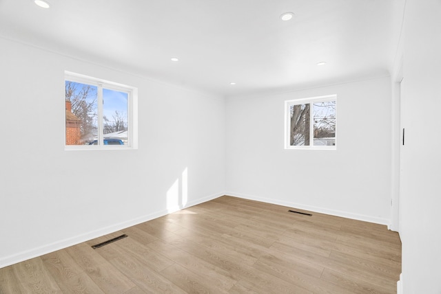 spare room with plenty of natural light, visible vents, and wood finished floors