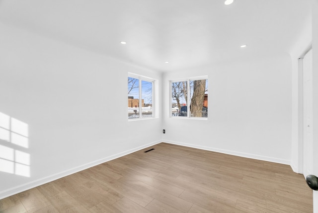 unfurnished room featuring recessed lighting, wood finished floors, visible vents, and baseboards