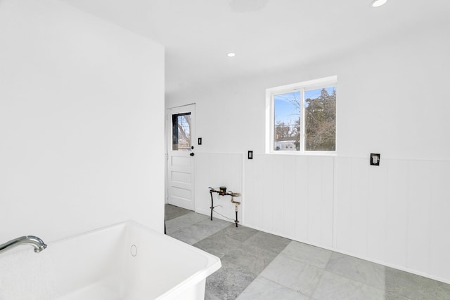 bathroom featuring recessed lighting, a wainscoted wall, and a freestanding bath