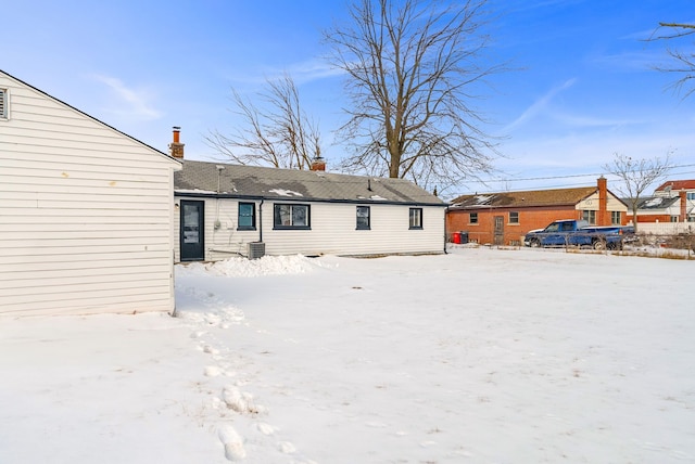 snow covered house featuring a chimney