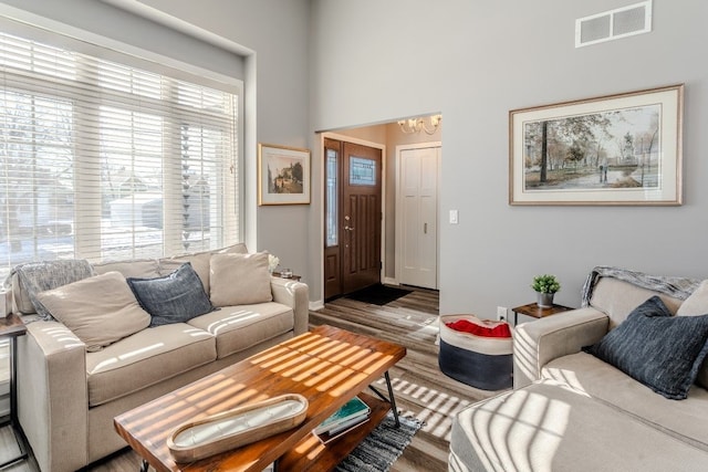 living area featuring visible vents, an inviting chandelier, and wood finished floors