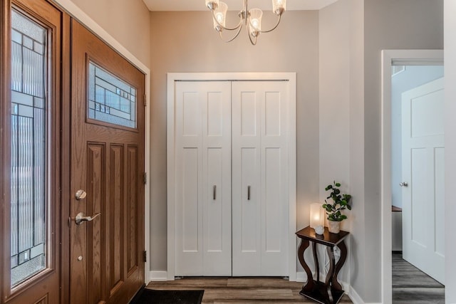 entrance foyer featuring baseboards, an inviting chandelier, and dark wood finished floors