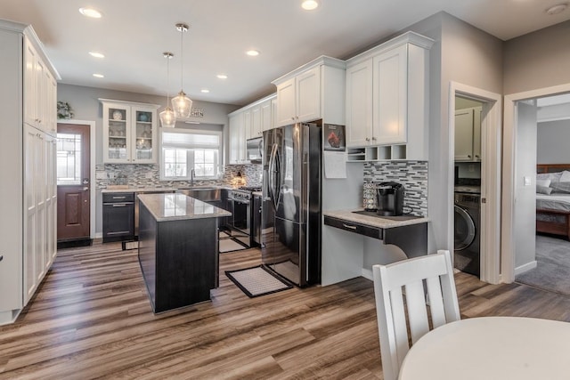 kitchen featuring a kitchen island, washer / dryer, stainless steel appliances, and wood finished floors