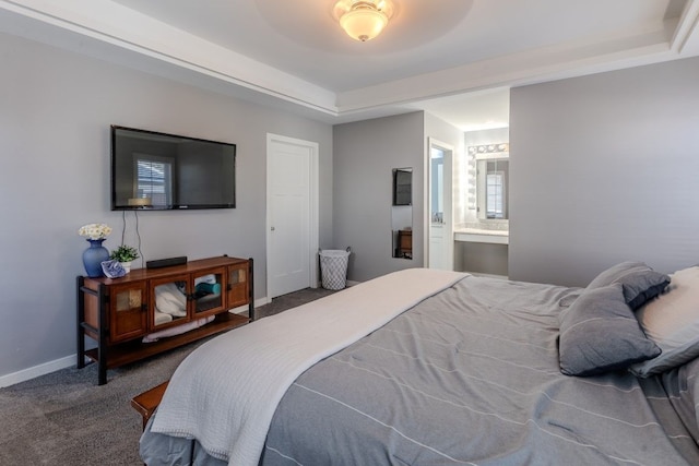 carpeted bedroom featuring connected bathroom, a raised ceiling, and baseboards