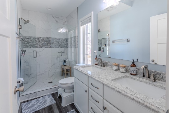 full bath featuring a sink, wood finished floors, toilet, and a stall shower