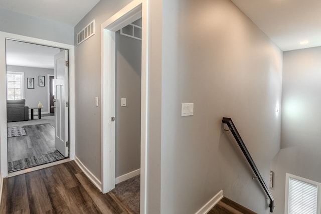 hall featuring an upstairs landing, visible vents, dark wood-type flooring, and baseboards