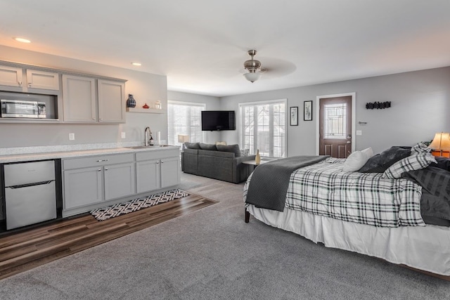 bedroom featuring light carpet, light wood-style flooring, a sink, fridge, and recessed lighting