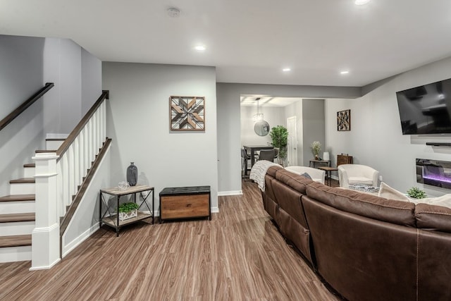 living room featuring recessed lighting, baseboards, wood finished floors, and stairs