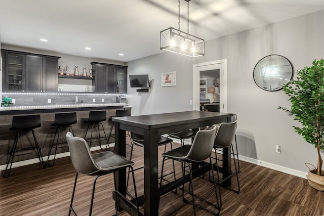 dining space featuring wet bar, recessed lighting, dark wood-style floors, and baseboards