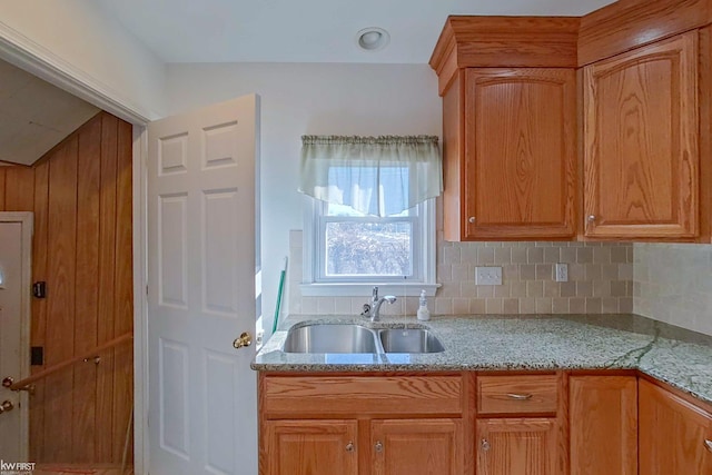 kitchen featuring a sink, decorative backsplash, and light stone countertops