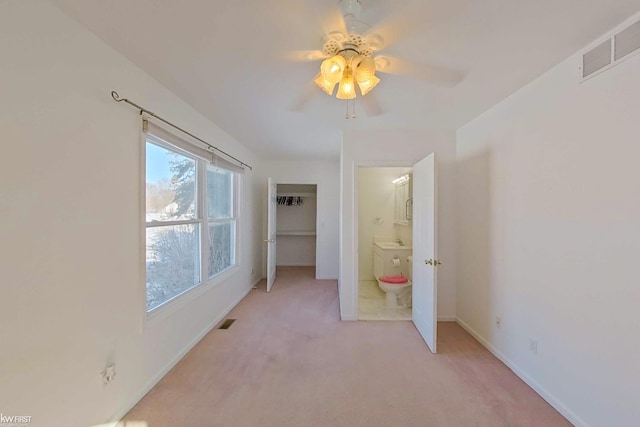 empty room featuring baseboards, visible vents, a ceiling fan, and light colored carpet