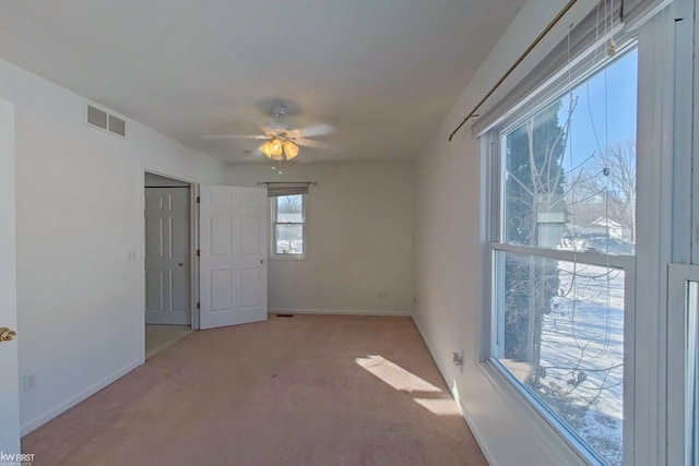 unfurnished room featuring baseboards, visible vents, ceiling fan, and carpet flooring