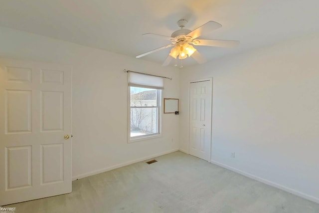 spare room featuring light carpet, visible vents, baseboards, and ceiling fan