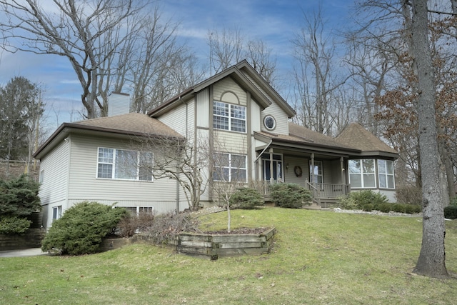 traditional-style home featuring a chimney, roof with shingles, covered porch, and a front yard