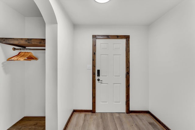 doorway to outside with arched walkways, baseboards, and wood finished floors