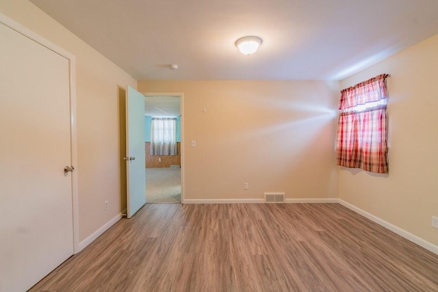 unfurnished room with wood finished floors, visible vents, and baseboards