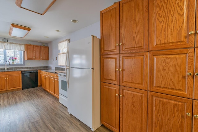 kitchen featuring white appliances, dark countertops, brown cabinets, light wood-style floors, and a sink