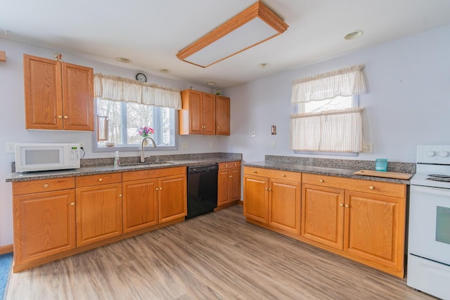 kitchen featuring brown cabinets, white appliances, a sink, and light wood-style floors