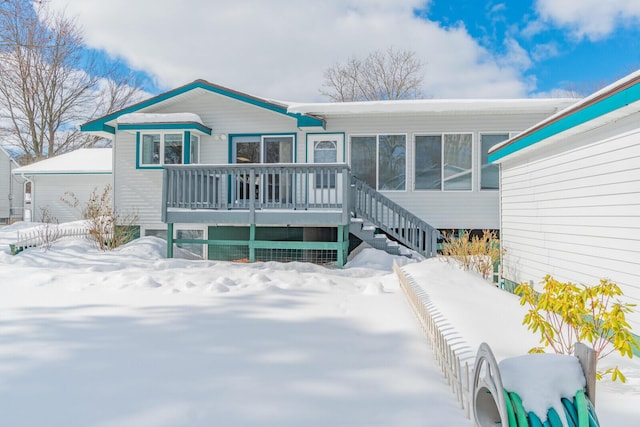 snow covered rear of property featuring a deck