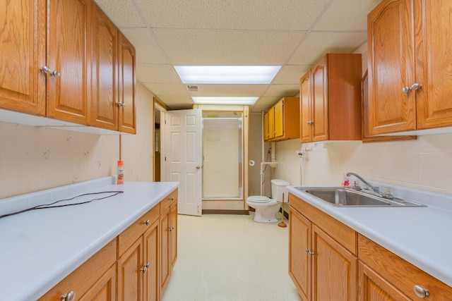 kitchen with a sink, light floors, brown cabinetry, and light countertops