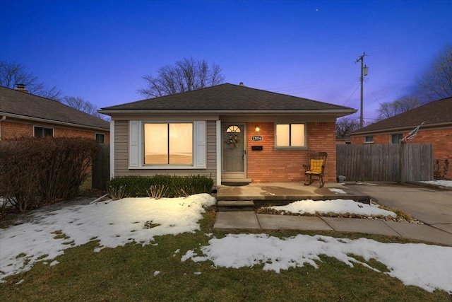 bungalow-style home featuring brick siding and fence