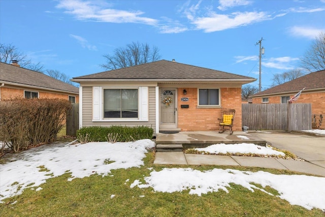 bungalow-style house with fence and brick siding